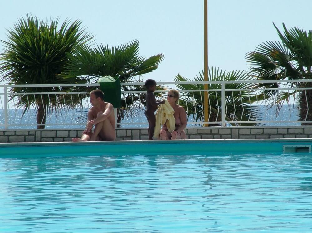 Photo of naturists in an outdoor pool - Getting rid of swimsuits